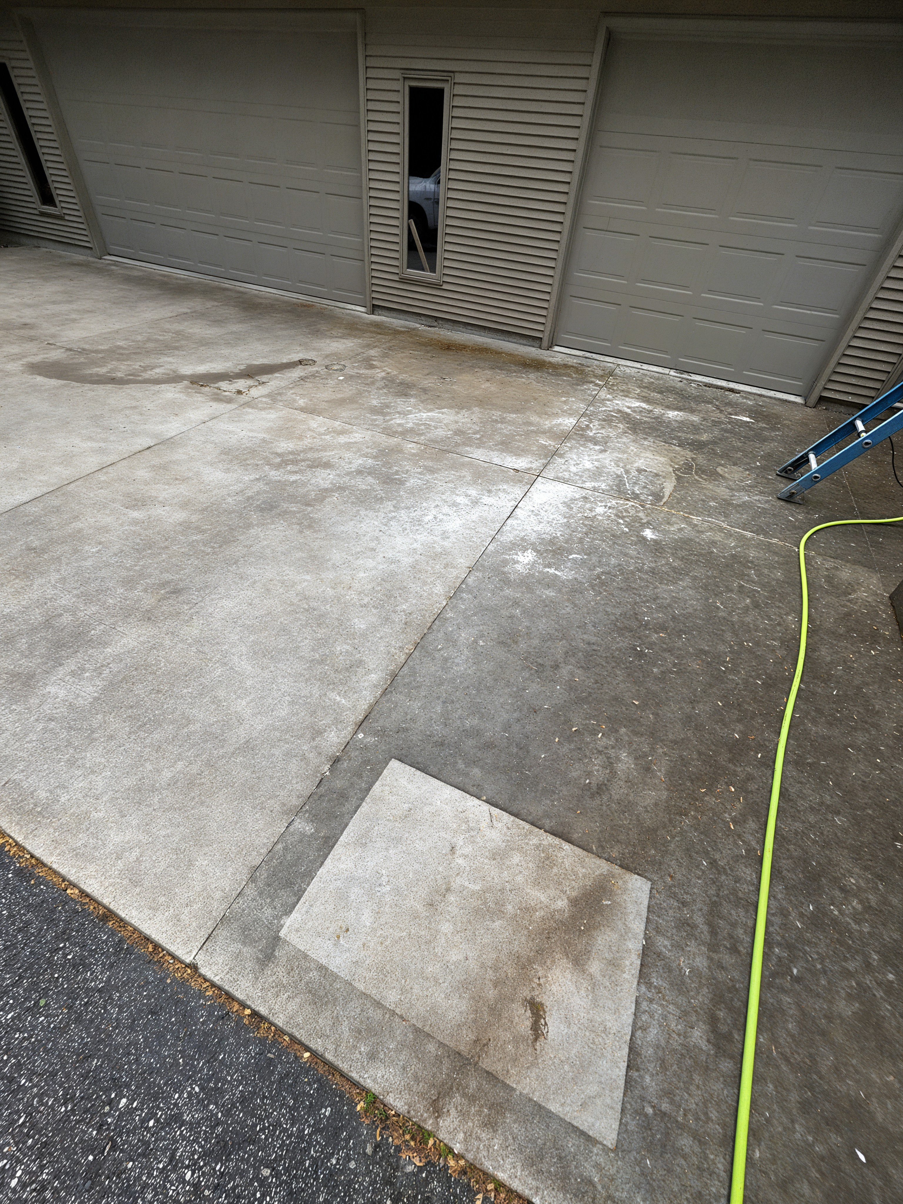 Before: dirty driveway with test patch and yellow hose